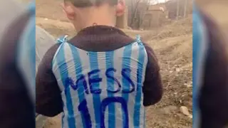 El niño afgano Murtaza muestra la camiseta de Messi de plástico.