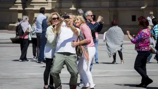 Unos turistas se fotografían en la plaza del Pilar.