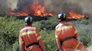 Dos bomberos observan las llamas cerca de la localidad de Sumacarcer en Valencia.