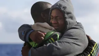 Dos inmigrantes se abrazan tras ser rescatados por los guardacostas italianos.