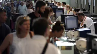 Personal de facturación de Vueling atiende a los viajeros en el Aeropuerto de El Prat este sábado.