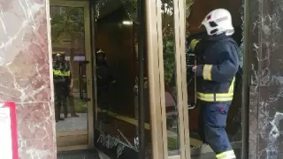 Un bombero atraviesa la puerta del edificio, rota tras la exposión