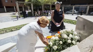 Marta Berdor, de blanco, y María Gracia Roca, colocan flores en el monumento de la casa cuartel.