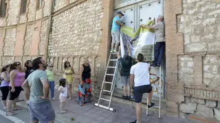 Un grupo de vecinos cuelga el cartel en la fachada del antiguo asilo de San José.