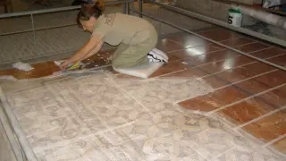 La restauradora cubre el mosaico ubicado en la entrada antes de proceder a su extracción.