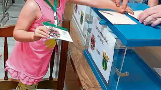 Una niña introduce su papeleta en la urna, durante la votación del pleno infantil del Ayuntamiento de Jaraba.