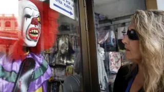 Una mujer observa un dizfraz de payaso diabólico expuesto en una tienda valenciana
