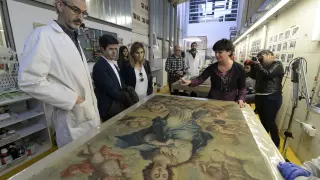 El alcalde, segundo por la izquierda, observa una de las pinturas que se restauran en la escuela.