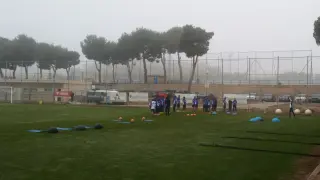 La plantilla del Real Zaragoza, en el inicio del entrenamiento de este jueves bajo la niebla y el frío de la Ciudad Deportiva.