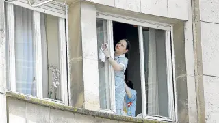 Una empleada del hogar limpiando ventanas en una imagen de archivo.