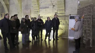 Un grupo de visitantes atiende a las explicaciones de la guía sobre la puerta del palacio prioral del siglo XIII, ayer en Sijena