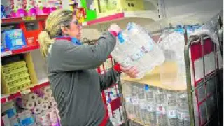 Una empleada del supermercado Dia de Calatorao repone botellas y garrafas de agua.