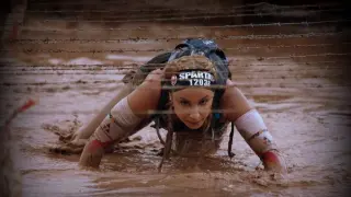 Natalia Castiella reptando bajo un alambre de espino en una Spartan race.