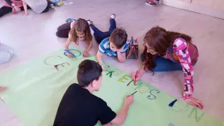 Los niños pintan una pancarta, en el centro de tiempo libre El Globo de Parque Goya