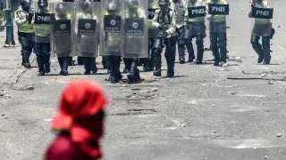Varios policías armados intentan sofocar la revuelta en Caracas.