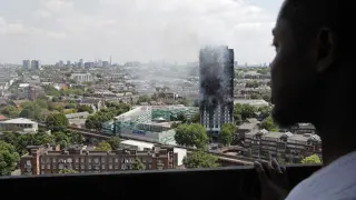 Un hombre observa el edificio devastado por las llamas.