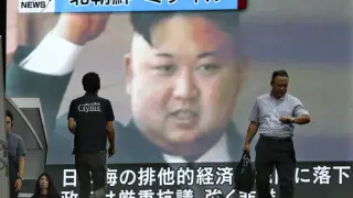 Varios viandantes pasan ante una pantalla gigante de televisión que muestra un retrato del líder norcoreano Kim Jong-un
