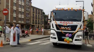 El párroco lanzando agua bendita a uno de los camiones que ha participado en el desfile.