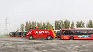 Una grúa con un autobús averiado pasa por delante de los once nuevos vehículos que se incorporaron a la flota el pasado mes de noviembre.
