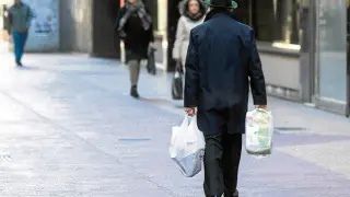 Un transeúnte pasea por Zaragoza con dos bolsas de plástico.