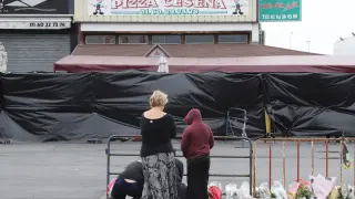 Varias personas depositan flores frente a la pizzería donde ocurrió el atropello mortal.