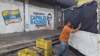 Un trabajador ordena su negocio ante una pintada electoral de la oposición.