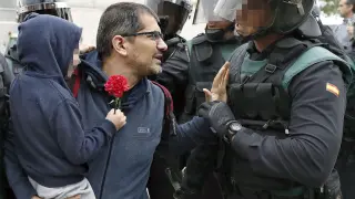 Un padre sostiene a su hijo en brazos frente a un Guardia Civil durante el 1-O.