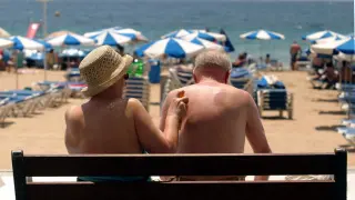 Dos turistas toman el sol en la playa de Benidorm, una de las más típicas dentro del programa del Imserso.