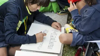 Un grupo de niños escribe un cartel en el parque.