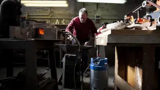 Román Sanz trabaja el acero después de calentarlo en su pequeña estructura de ladrillo, alimentada por dos sopletes.