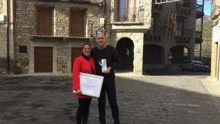 Raquel Rodríguez y el alcalde de Boltaña posan con el premio recibido esta semana al mejor campin familiar en la plaza del pueblo.