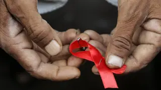 Un hombre sujeta un lazo rojo, símbolo de la lucha contra el sida.