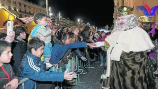 Numeroso público esperaba a Sus Majestades en la plaza del Pilar. En la imagen, el rey Melchor saluda a un grupo de niños que llevaba dos horas esperando.