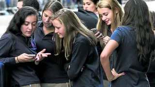 Una estudiante de Nueva York muestra a sus compañeras el contenido de un mensaje en su teléfono.