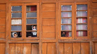 Varias mujeres miran por una ventana en la Cachemira india