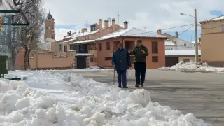 Dos vecinos de Villafranca del Campo, en el Jiloca, pasean por la calle, con nieve a ambos lados.