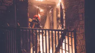 Un bombero, apagando el virulento incendio en el bloque de apartamentos de Benasque