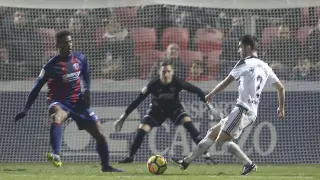 El portero Álex Remiro observa el intento de disparo de un jugador rival durante el Huesca-Oviedo mientras Jair intenta taparle.