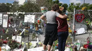 Dos personas mirando el memorial en homenaje a los 17 asesinados en el tiroteo.