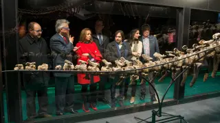 La consejera de Cultura, Mayte Pérez, y el director de la Fundación Dinópolis, Luis Alcalá, así como otros asistentes al acto, junto a la gran cola de un dinosaurio