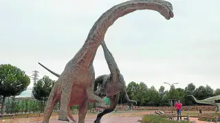 Un visitante de Dinópolis fotografía la reproducción de un Tastavinsaurus y un Baryonyx luchando entre sí.