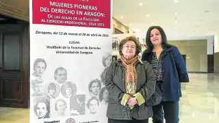 Carmen Teresa Aguelo y Belén Causapé junto al cartel que anuncia la exposición en la Facultad de Derecho