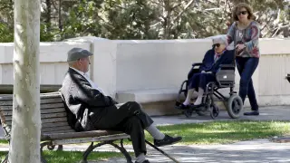 Imagen de un jubilado en el parque de los Fueros de Teruel, donde una mujer pasea a su vez a una anciana.