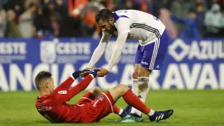 Borja Iglesias, delantero del Real Zaragoza, ayuda a Álex Remiro, portero del Huesca, en el último derbi aragonés.