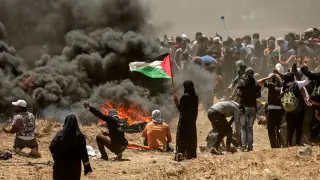 Una mujer palestina sostiene una bandera en medio de las protestas