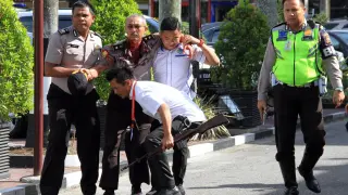 Varios policías evacuan a un compañero herido tras un ataque a la comisaria de Pekanbaru