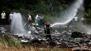 Un bombero refresca la zona donde se estrelló el avión