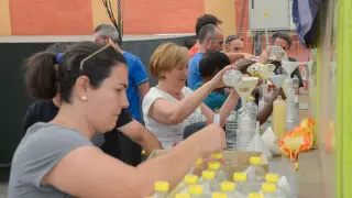Socios de la peña El Trago rellenan las botellas de alcohol para el fin de semana vaquillero