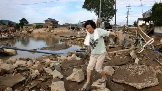 Una mujer camina por una carretera cubierta de barro después de la inundación en Kurashiki