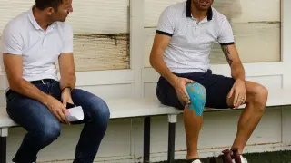 Toquero, con las muletas en el suelo y la rodilla dañada aún protegida, charla con el director deportivo Lalo Arantegui en el banquillo del campo del Tudelano, este sábado antes del partido amistoso del Real Zaragoza.